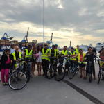 Gruppo di cicliste e ciclisti FIAB Genova al porto di Genova, con la Lanterna sullo sfondo